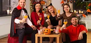 Carnival_Cruise_Tips Group of friends in Halloween costumes, smiling and holding drinks at a festive gathering.
