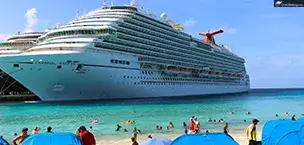 Carnival_Cruise_Tips Carnival Breeze cruise ship docked on the beach, with people swimming and relaxing under umbrellas.