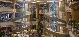 Cruise_Holidays Elegant cruise ship atrium decorated for Christmas with grand staircase and blue chandelier.
