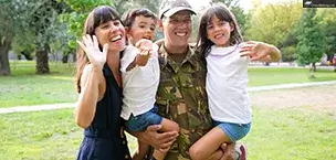 Daddy holds two kids, mom waves and hugs