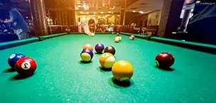 A young man attempts to hit the ball in billiards.