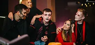 Disney_Cruise_Tips Five friends in spooky costumes celebrating Halloween with pumpkins and eerie decor.