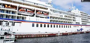 Large cruise ship docked at harbor with lifeboats