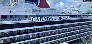 First_Time_Cruisers Carnival Dream cruise ship with iconic red, white, and blue funnels against a cloudy sky.