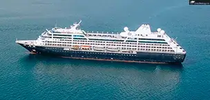Luxury_Cruises A luxury cruise in calm blue ocean, with lush green hills in background and small boat in foreground