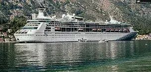 Large cruise ship docked, mountains in background