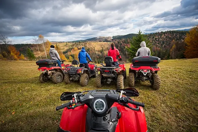 From the perspective of a quad bike. A beautiful landscape is enjoyed by four men on an ATV