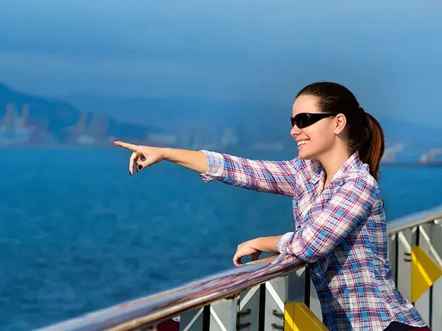 On a cruise ship deck, a beautiful adult woman points to something