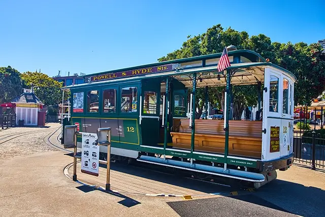 At the end of the path is an empty green tourist streetcar trolley with a rotating circular platform