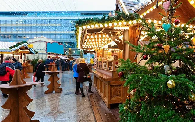 At the Kaiser Wilhelm memorial church in Winter Berlin, Germany, there is a Christmas market with stalls and a tree. Decorations for the Advent fair and craft stalls on the bazaar