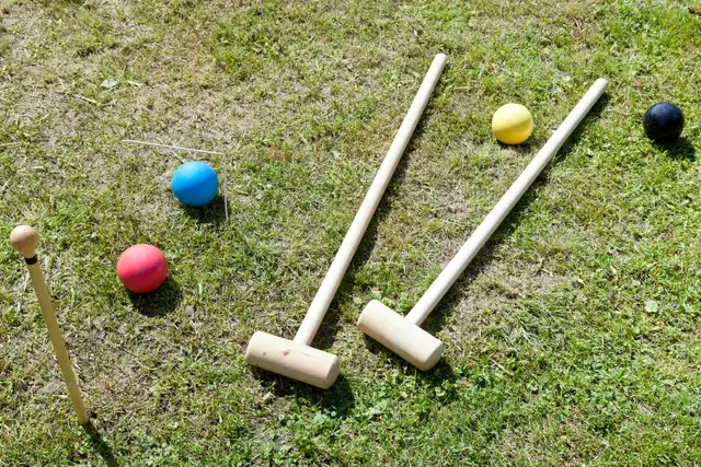 A game of croquet is being played on a green lawn