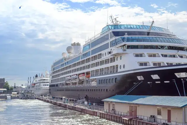 Passenger ship anchored at the port's pier on a sunny day. seaport. The ship takes passengers on a sea cruise. The tourism of the sea. Traveling through Europe. In the seaport, a white ship stands