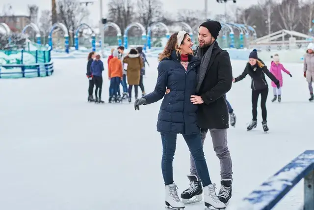 Young couples enjoying winter time at the ice rink while hugging