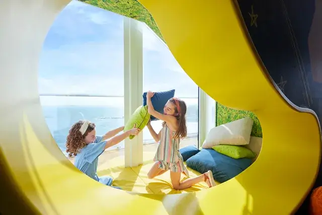 An icon of the seas, kids playing pillow fights in the Ultimate Family Townhouse, excitement, ocean views.
