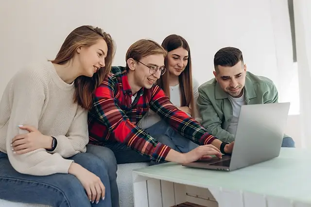 A group of friends is looking at something on their laptops