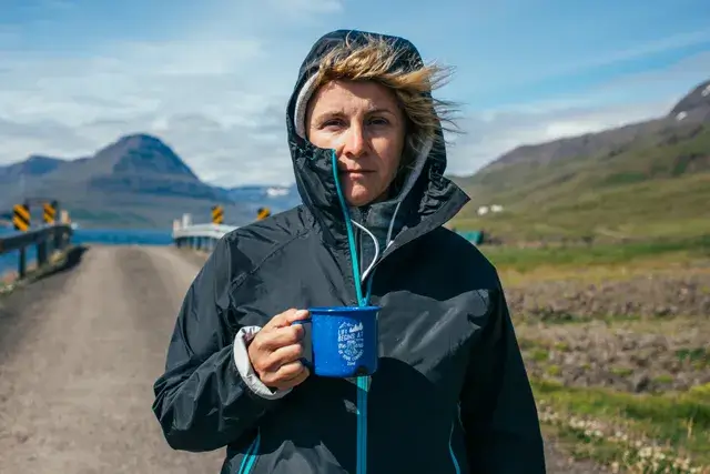 During a hike trip in Iceland, a woman holds a camping mug