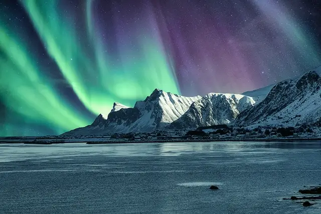 In the Lofoten Islands, the northern lights are shown above a snowy mountain with the aurora borealis