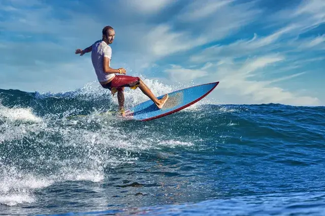 During a sunny day, a male surfer is riding a blue wave on a blue wave