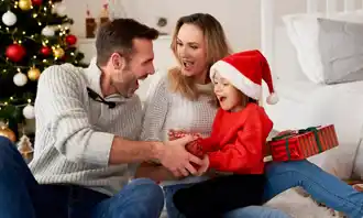 father giving christmas present to his kid and wife looking at him happily