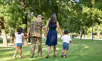 military man walking in park with his wife and kids