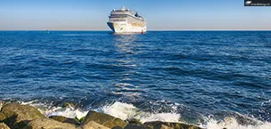 a large oceania cruise ship is sailing on a calm blue ocean. the sky is clear and blue.
