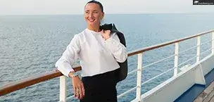 a smiling woman in a grey jacket on ocean water